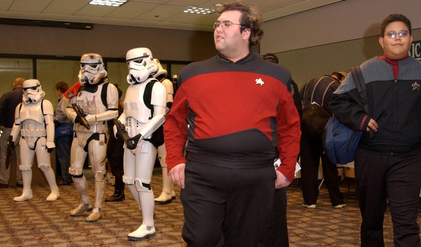 People in Star Trek uniforms next to people in Stormtrooper costumes.